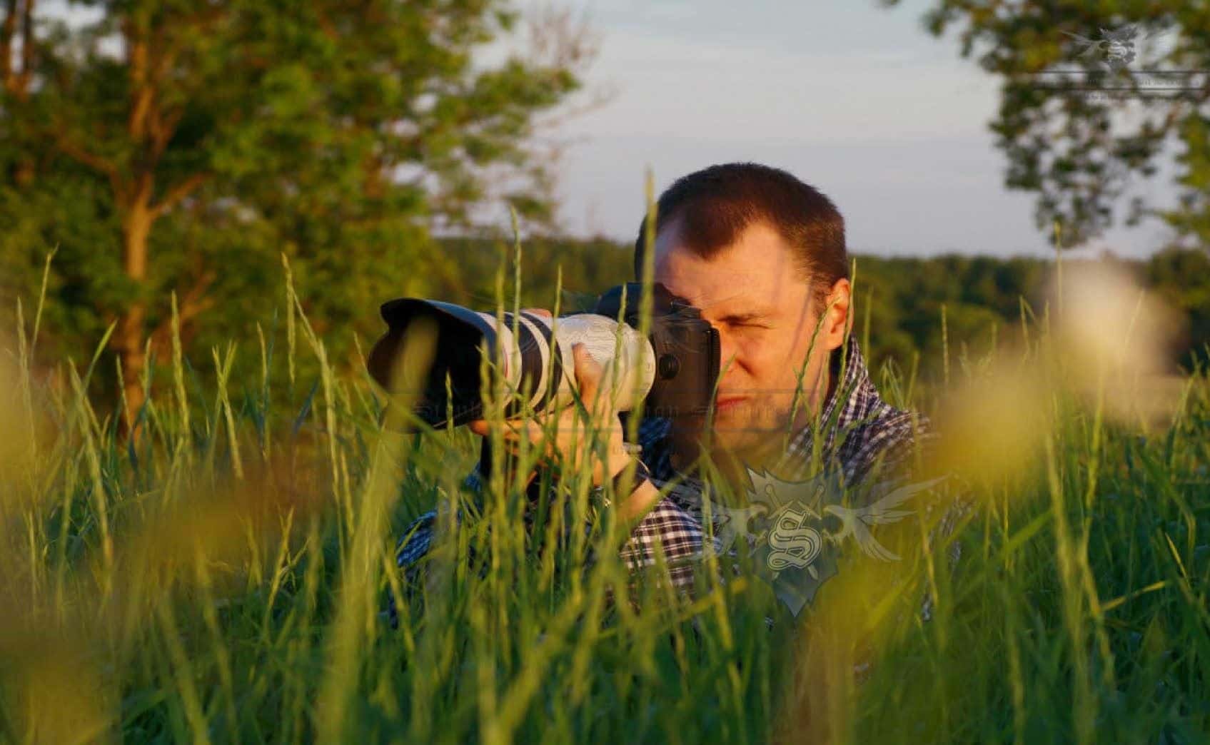 Orange County Private Investigator Stryker Investigation, a private investigator in camouflage clothing crouched in tall grass, conducting surveillance.